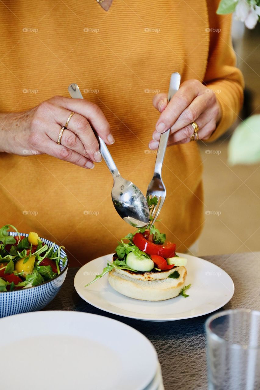 Person in orange sweater picking food from a buffet 
