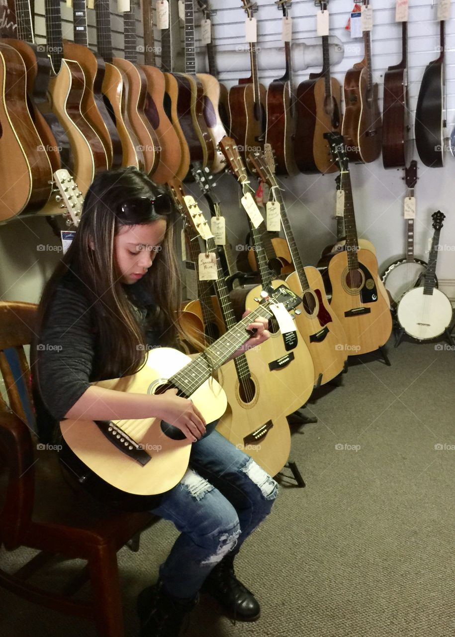 Girl sitting with guitar in the store