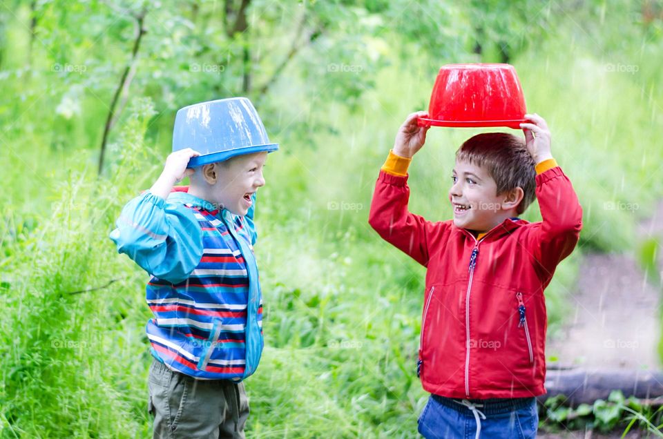 Children Playing in Rainy Spring Day with Buckets on Their Heads