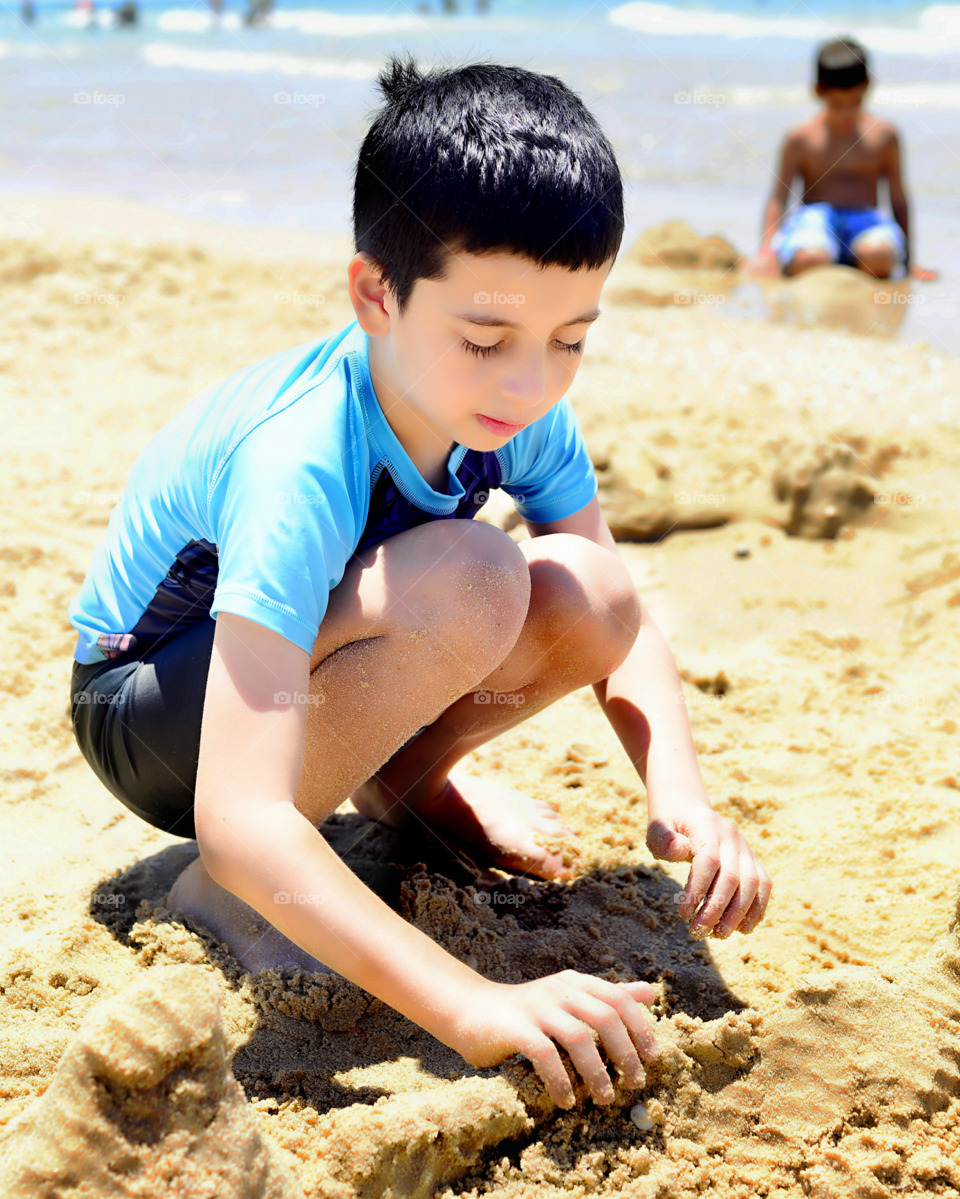 Boy playing with sand on beach