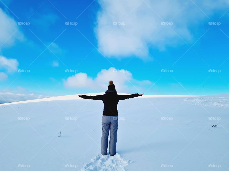 woman from behind on snowy mountain touches the clouds