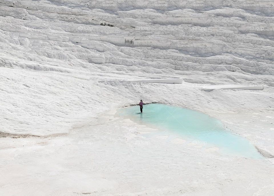 Tiny human taking a photo of unique white landscape 