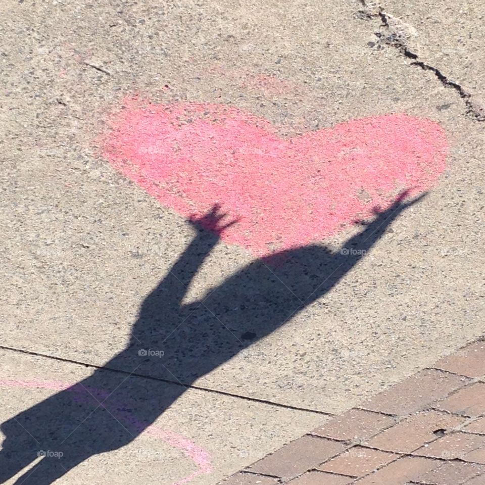 Shadow fun with chalk . Playing with chalk , on a sunny day caught my daughter using her shadow to hold the heart . 