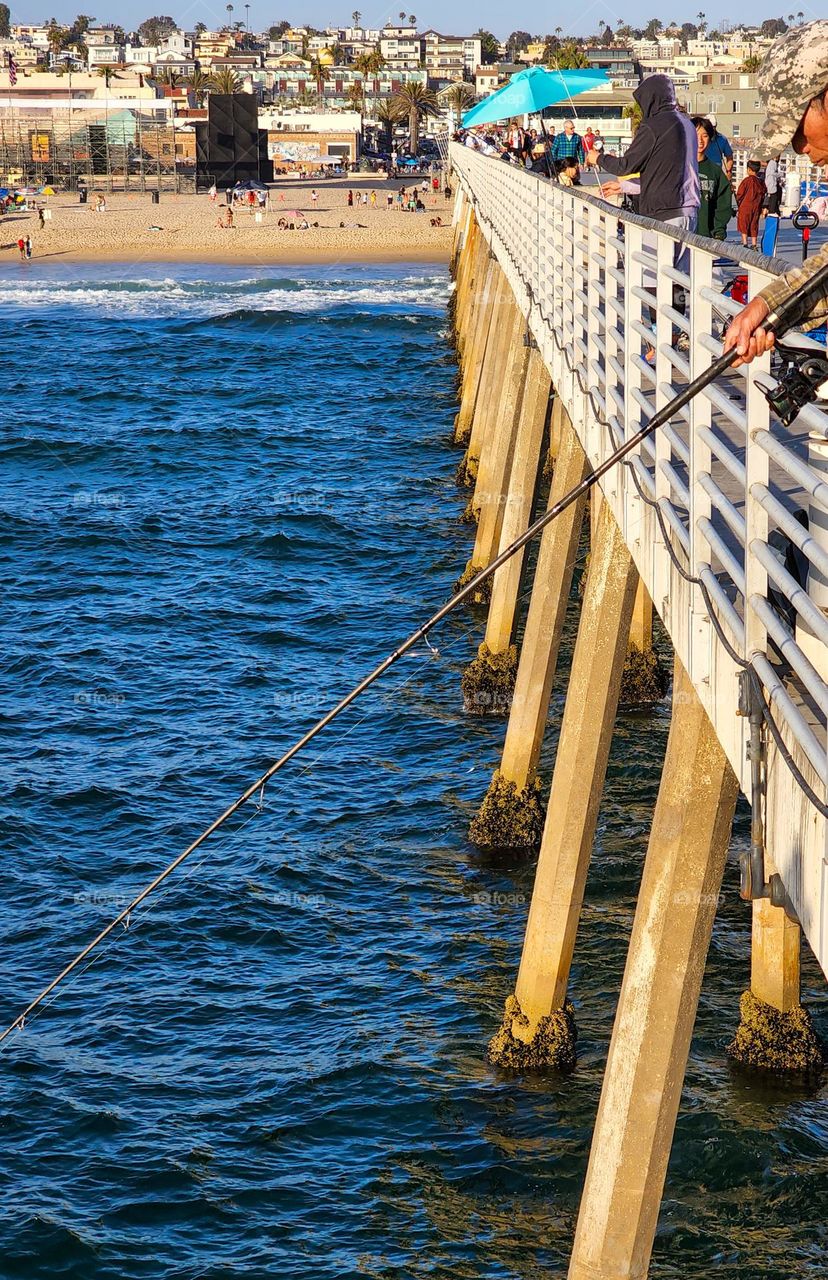 A fisherman works his line off a pier in the Pacific Ocean
