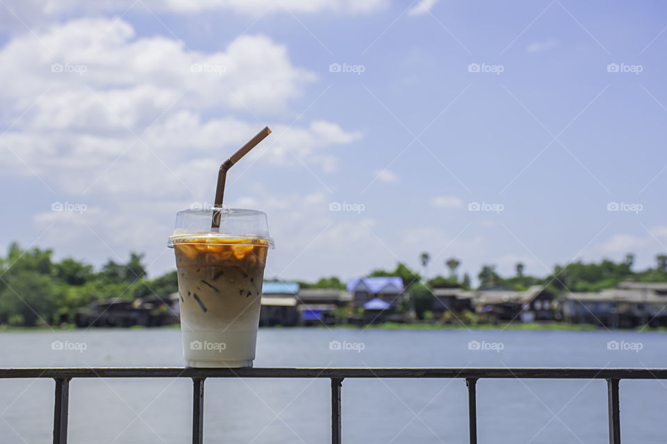 Glass of cold espresso coffee on the iron balcony Background views of the river and the home.