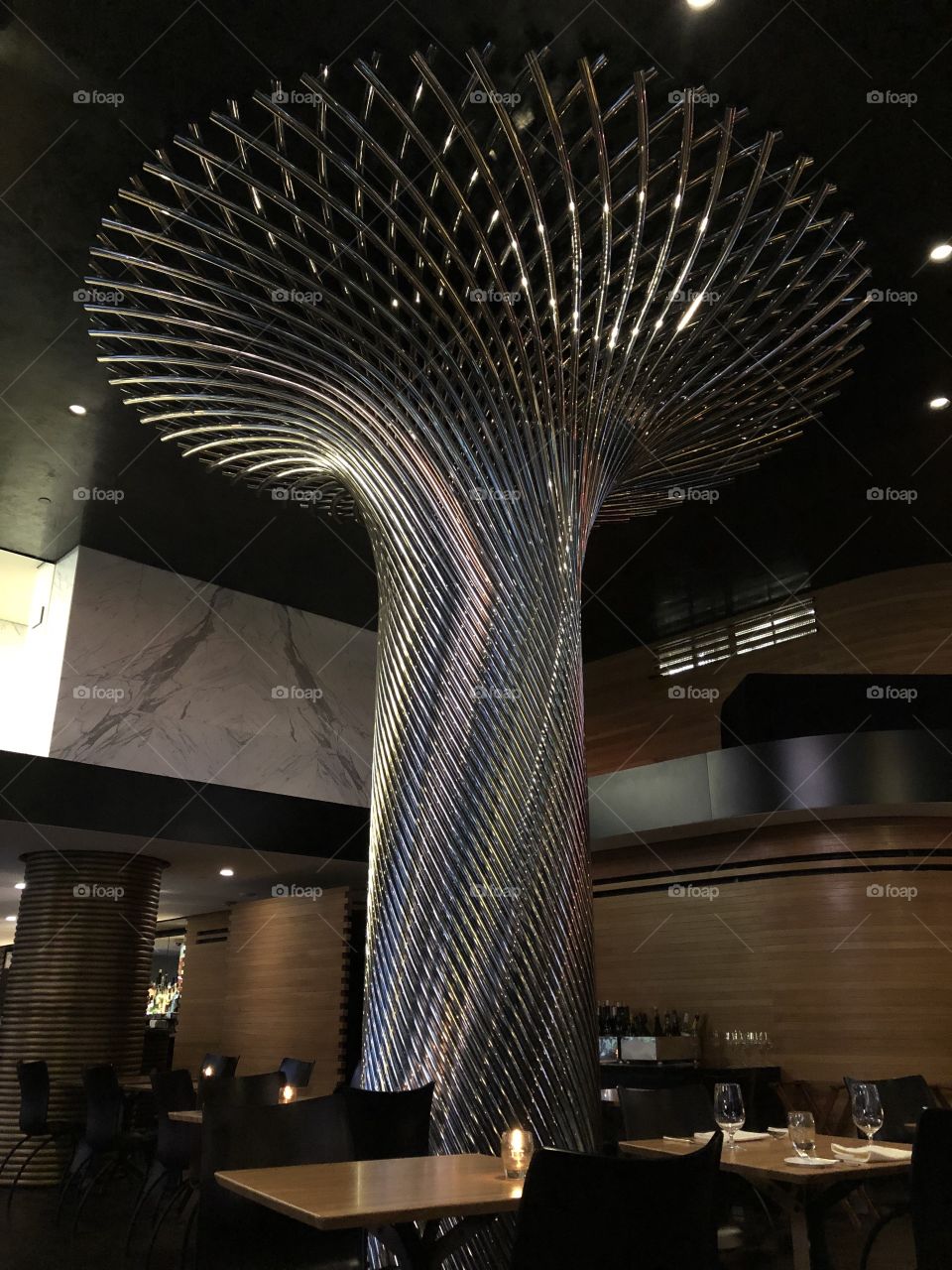 Shiny metal bars twist upwards in a circular pattern to create a stunning centerpiece of a modern restaurant