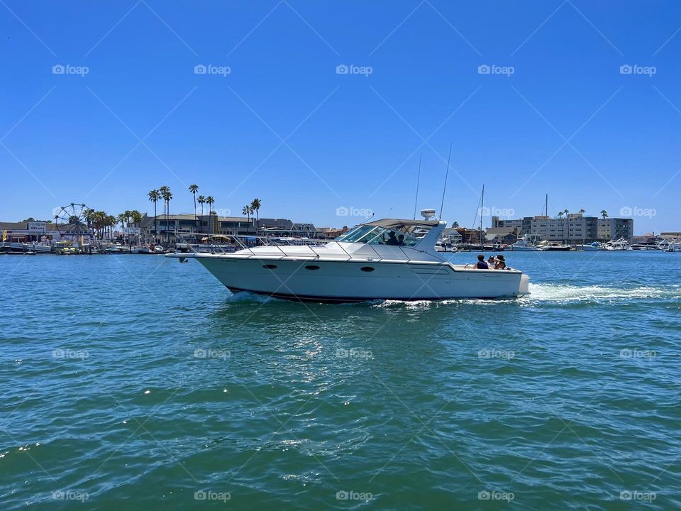 Balboa Island Ferry crossing the Entrance Channel in Newport Beach California with a boat in front of it 