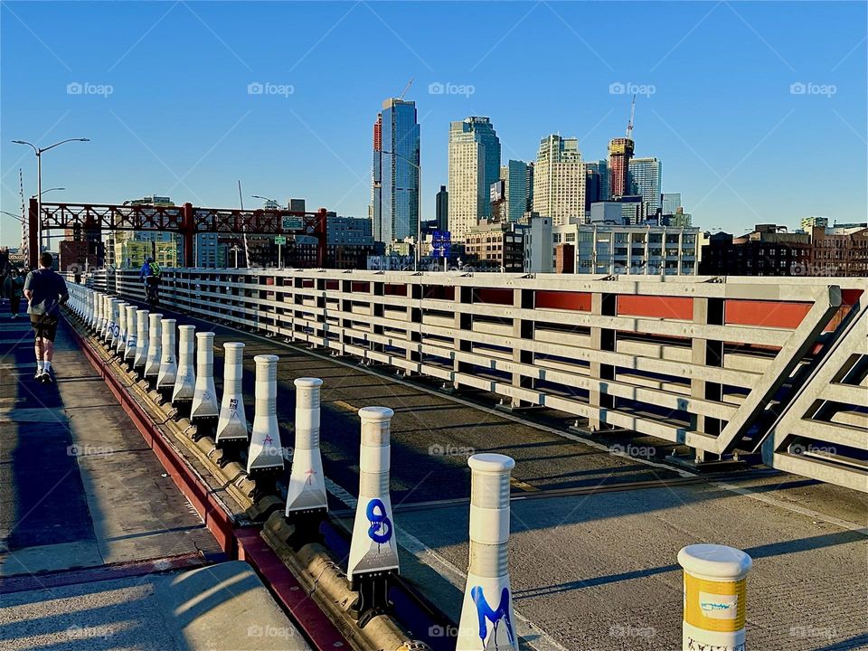 This is the pedestrian and the bicycle lane of the “Pulaski Bridge” at “Newtown Creek” that connects “Greenpoint”, Bklyn to LIC in the direction we are facing. The setting sun accentuates the strong geometry of the bridge. 2024. Hypnotic Productions