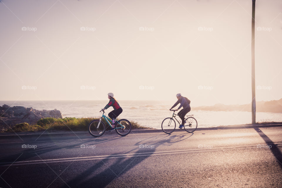 Two cyclists in their morning routing cycling by the streets near of the Pacific Ocean 