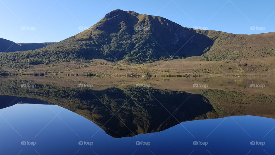 An hill reflected in the water of a lake. Norway.