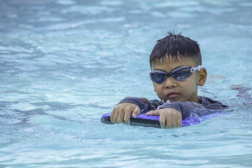 Asian boy learned to swim in the pool.