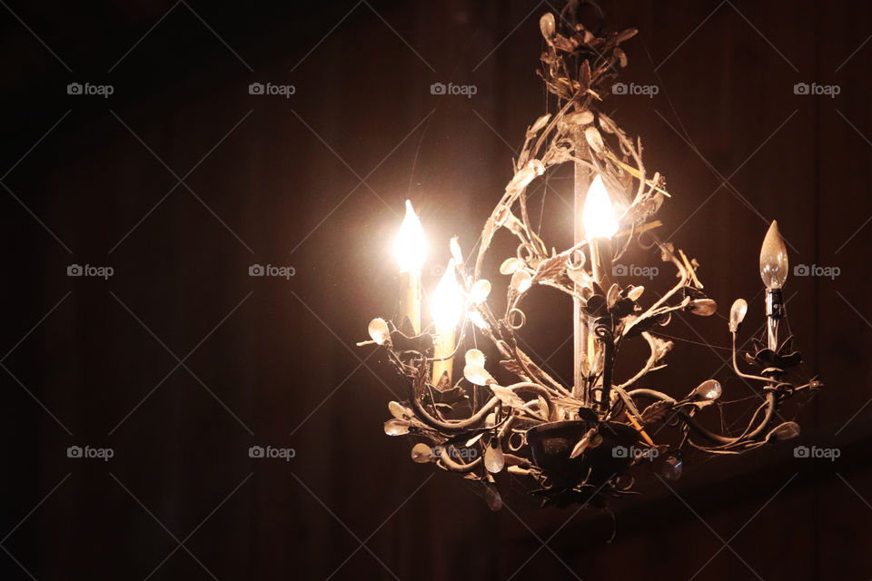Bright shining, old metal chandelier in darkness