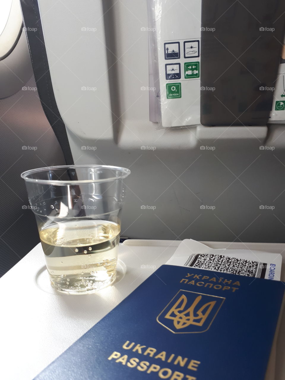 Glass of white vine on the table near the passport in airplane