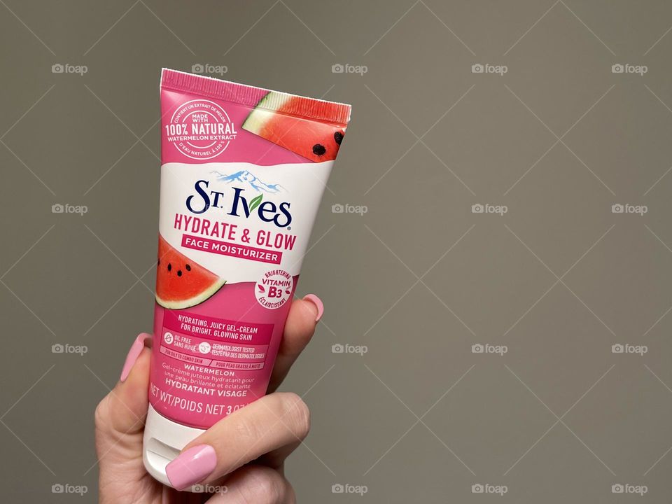 St. Ives face cream in female hand on the grey background 