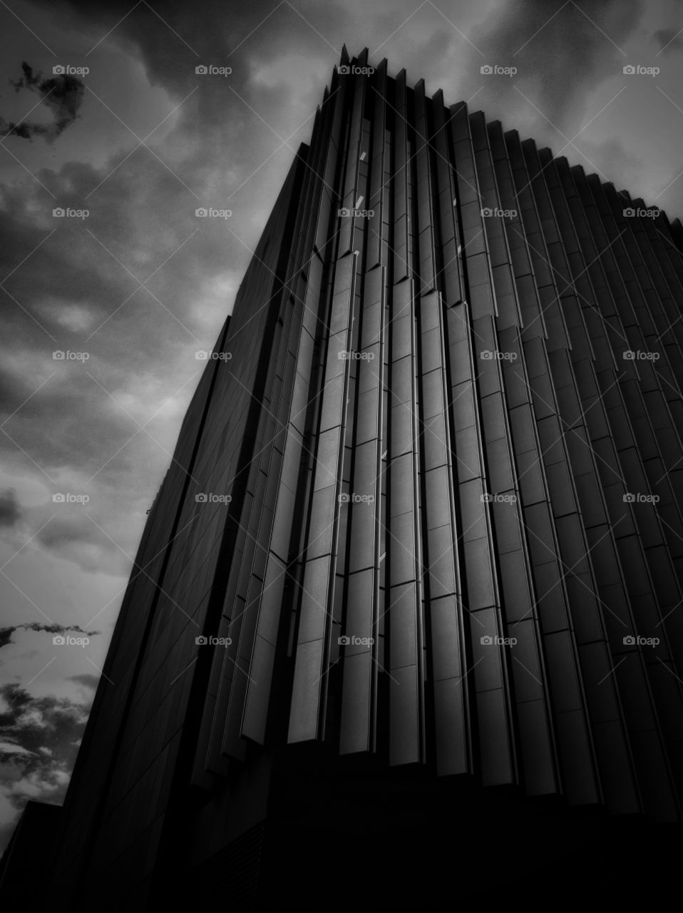 Tall building with contemporary design as viewed from street level. Image in monochrome with high contrast.