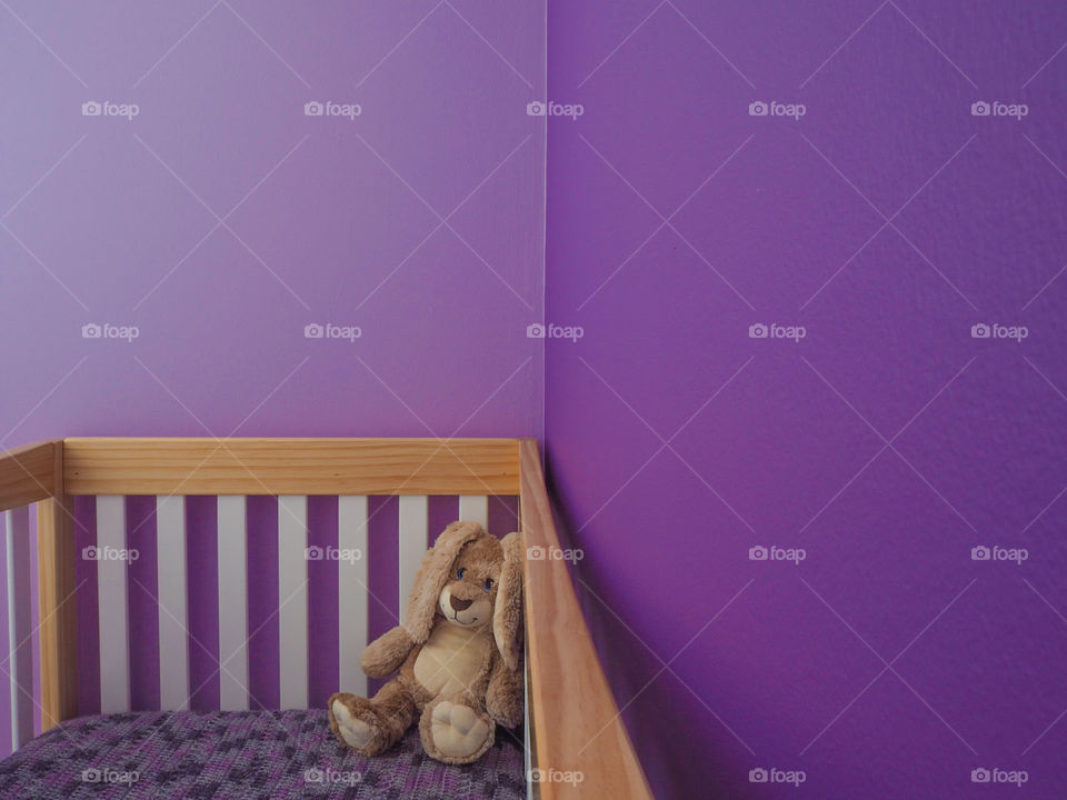 Purple baby nursery with bunny and blanky in the crib.