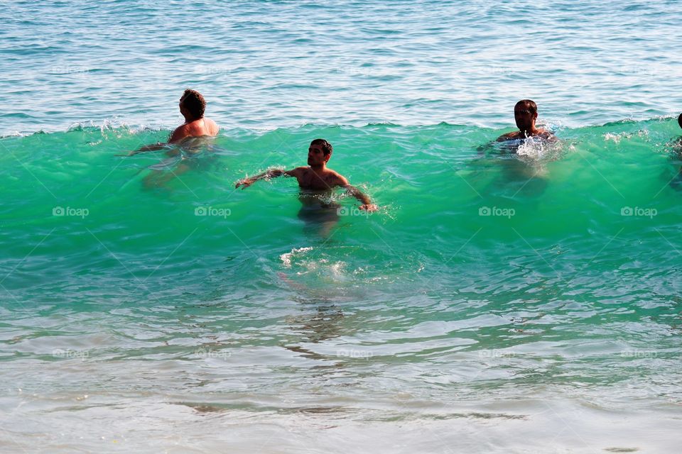 three men in a  wave