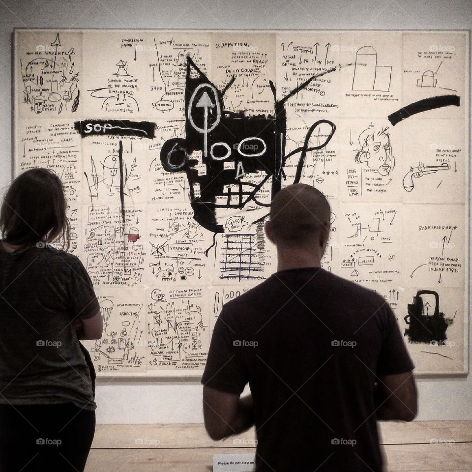 Brooklyn Museum. This is a photograph of two people looking at a painting done by Jean Michel Basquiat
