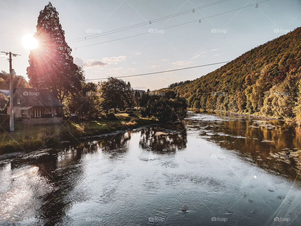 A landscape photo of the semois in the belgian ardennes taken from a bridge in vresse-sur-semois. the river is surround by authentic houses, forests and mountains.