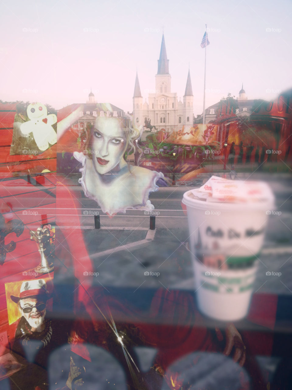 A blended photo of New Orleans French Quarter Jackson Square with  store front paintings from just dowb the street. Added in a cup of coffee from a well known establishment, maybe Cafe du Mon.
