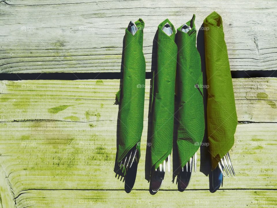 Cutlery in green tissue paper on a rustic table