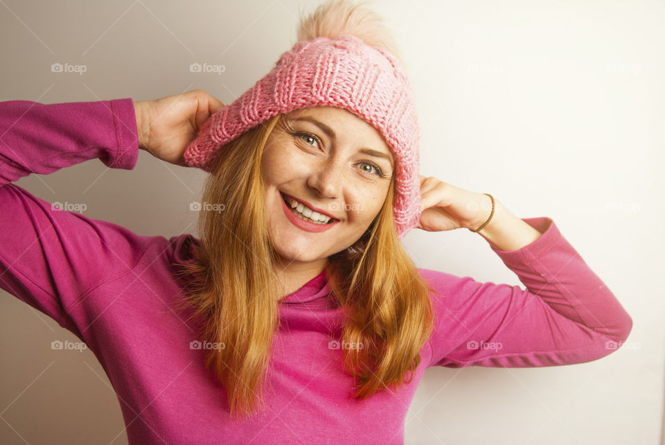 Young woman smiling,  with ping knitted hat. Winter is coming.