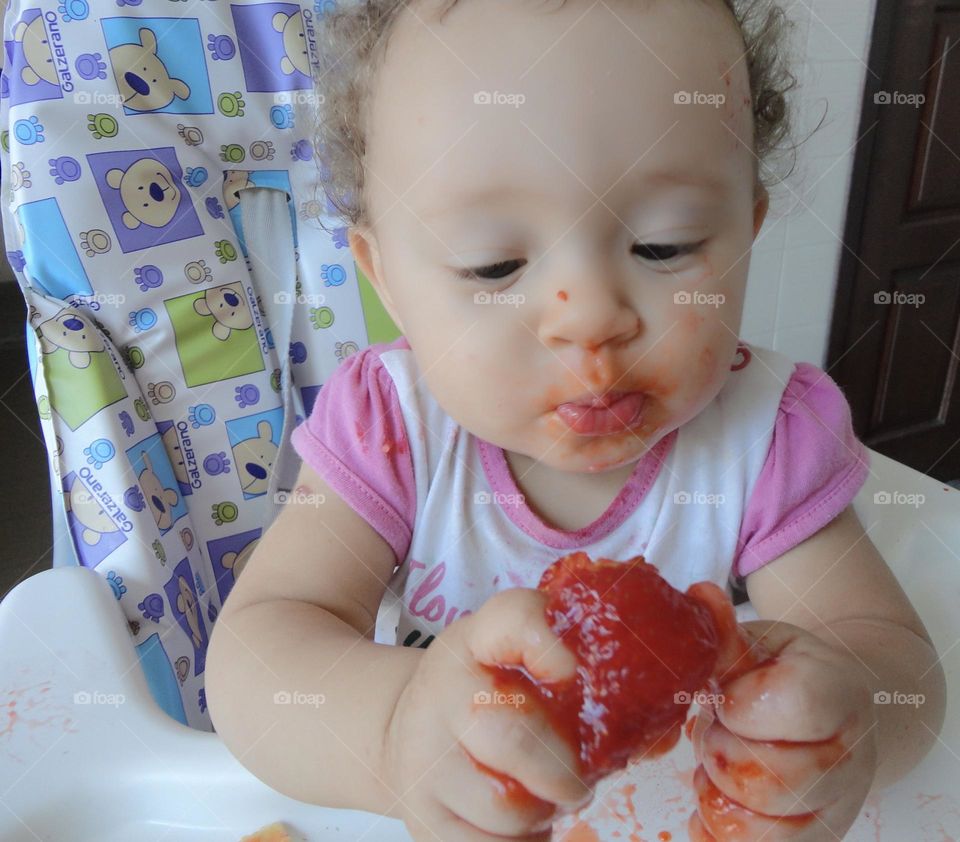 Curious expression of baby eating strawberry