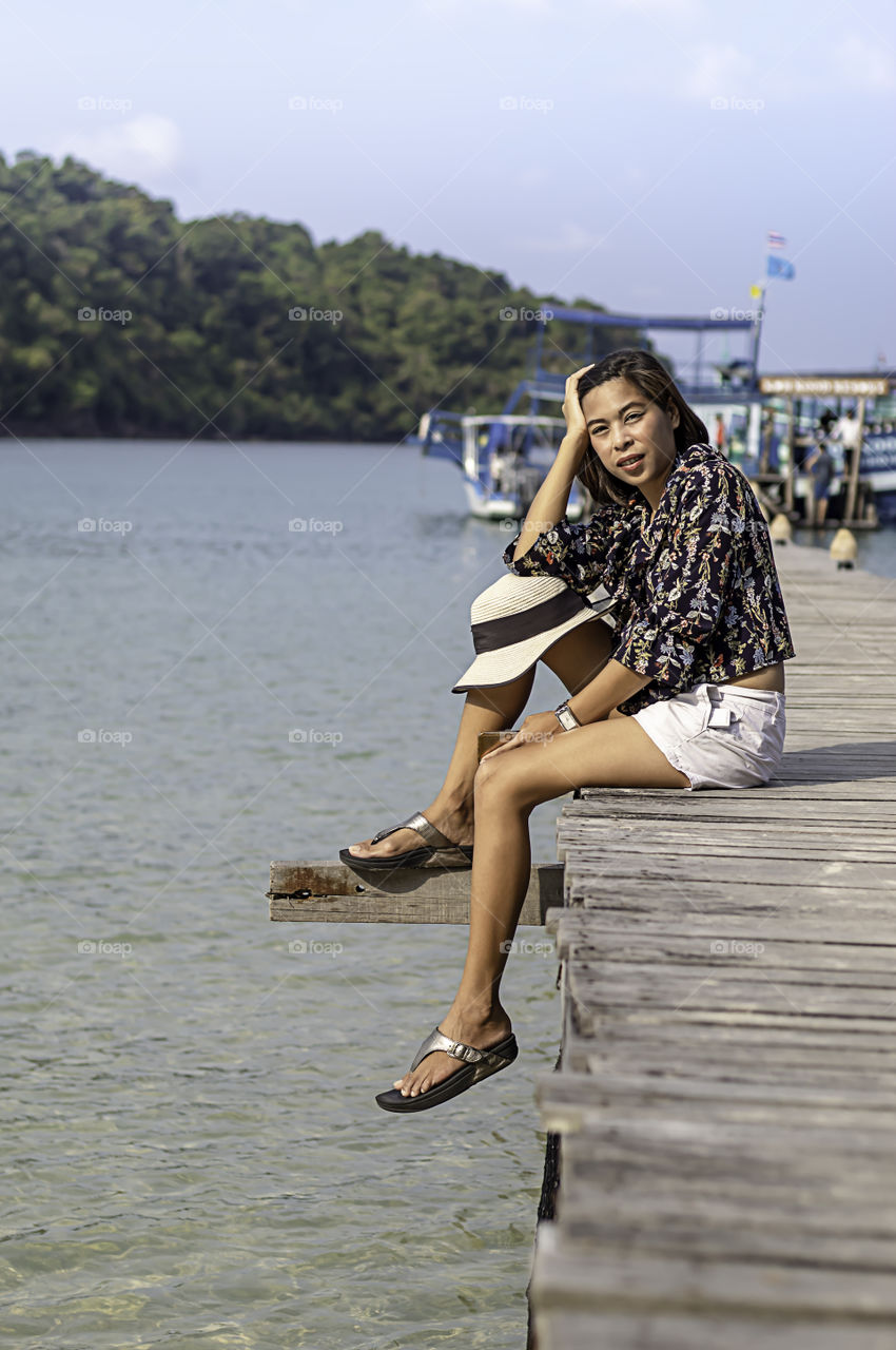 Women on the wooden bridge pier boat in the sea and the bright sky at Koh Kood, Trat in Thailand.