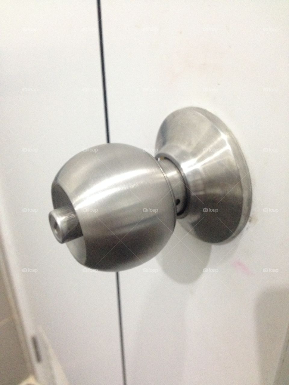 Stainless steel knob and white bath room door.
