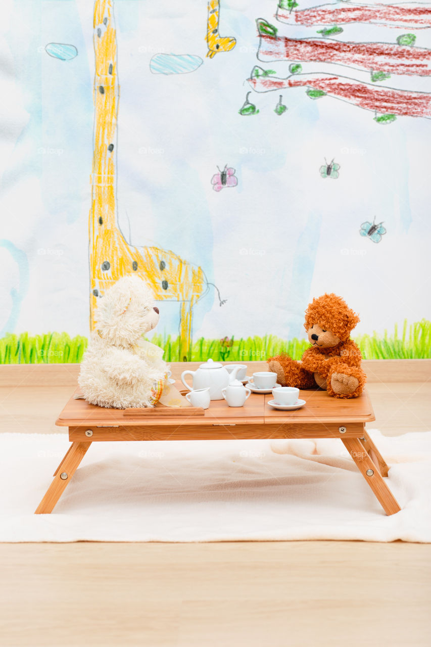 Child's tea set and stuffed toys arranged on small table in child room