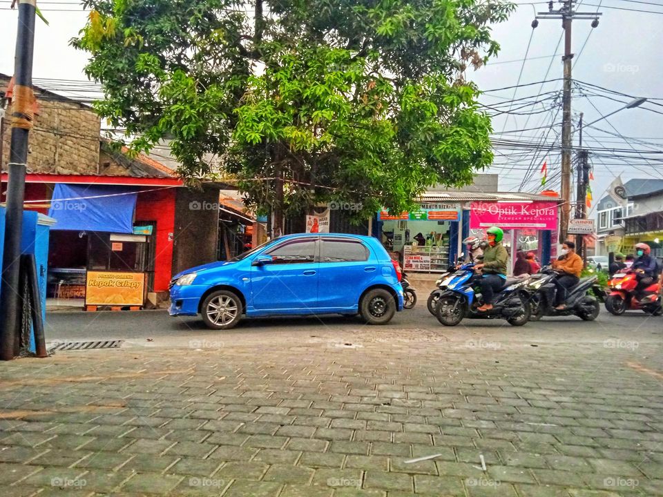 Blue car with motorcycles behind it