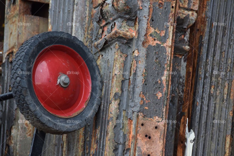 Red color story, pop of color on an old wagon wheel in junkyard