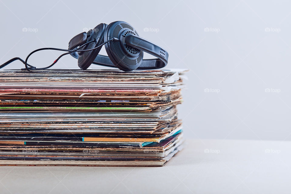 Stack of many black vinyl records, headphones put on the top of vinyls. Copy space for text. Candid people, real moments, authentic situations