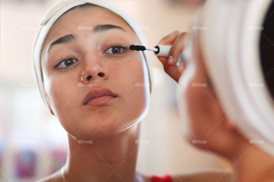 Young woman is using an eye mascara