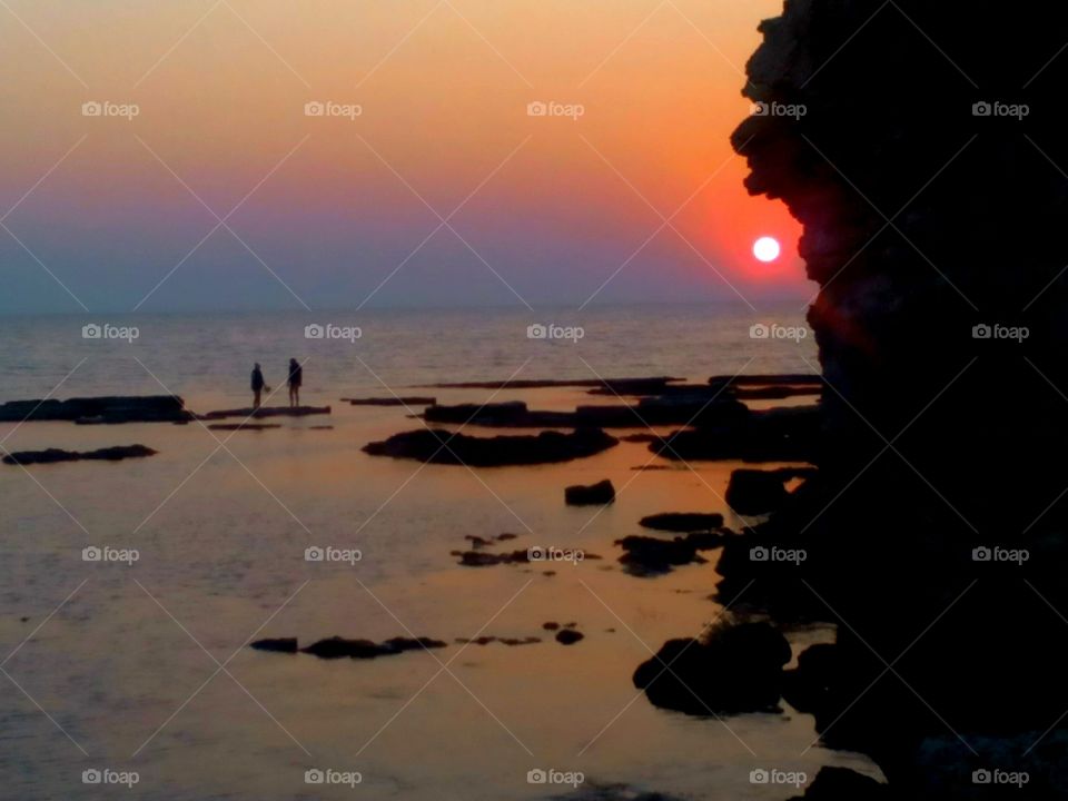 two peoples on a sea sunset