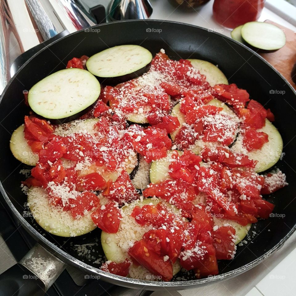 Eggplants and tomatoes on frying pan
