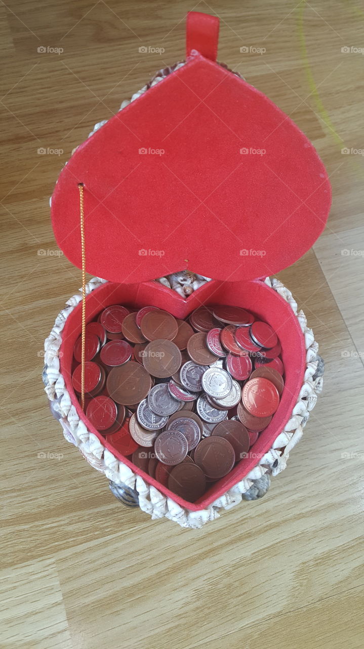 High angle view of coins in heart shape box