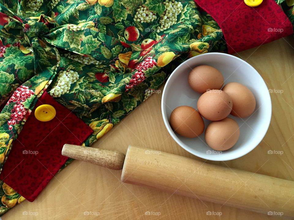 High angle view of rolling pin and eggs in bowl in kitchen