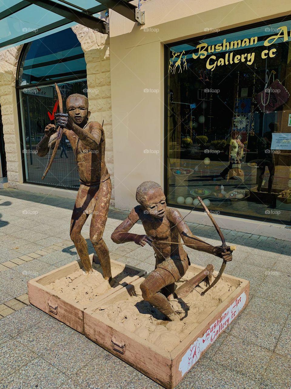 Two metal sculptures of San people (Bushmen) known as hunters and gatherers in front of an art gallery. 