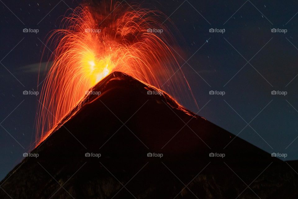 Volcano fuego exploding with orange lava at night in guatemala.