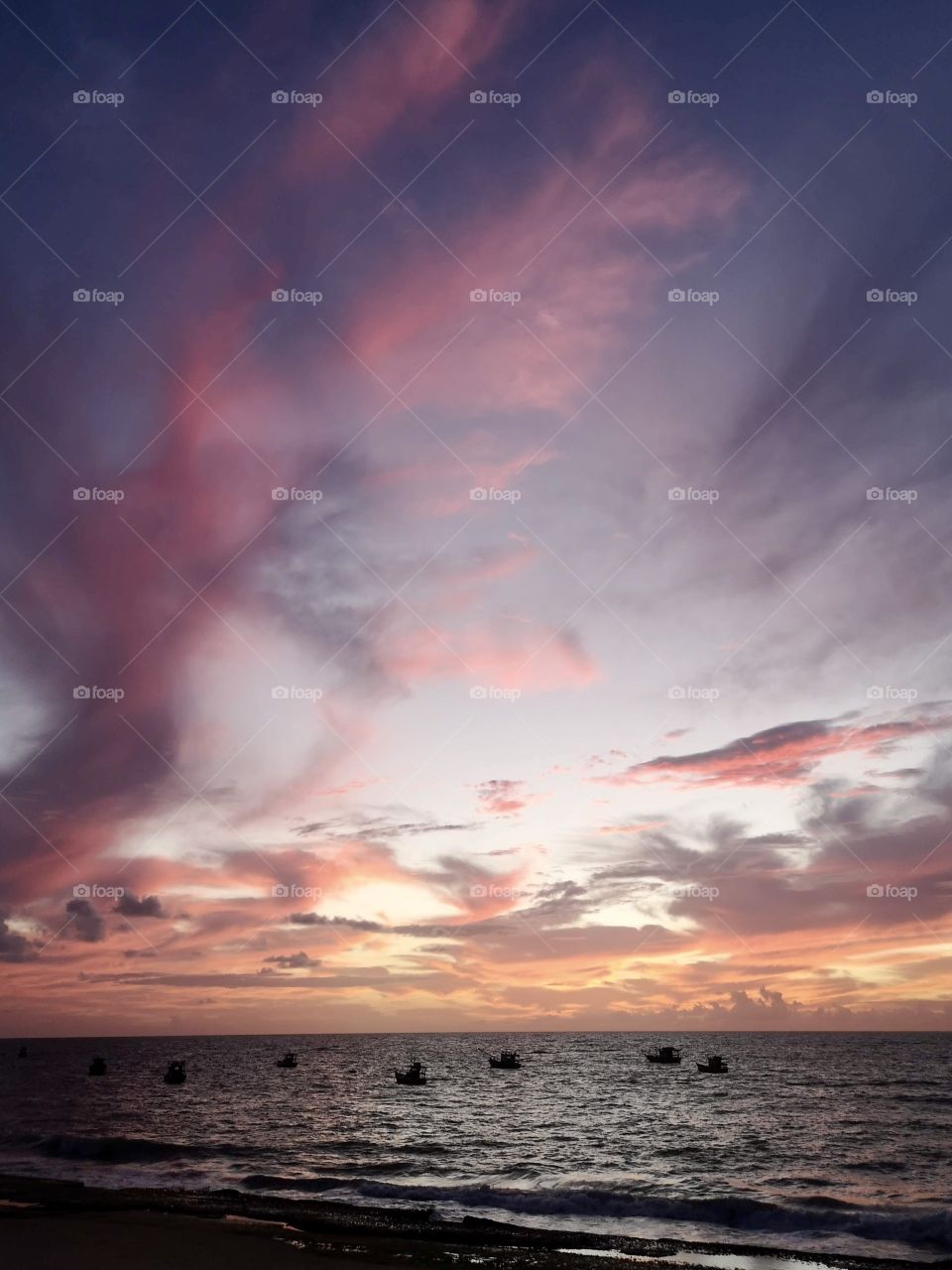 Reddish sky at dawn with boats and sea on the horizon
