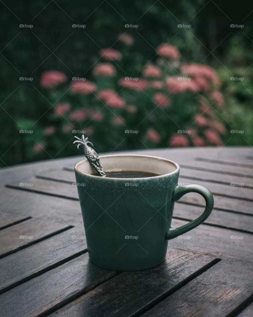 Green coffee cup on a table in a garden 