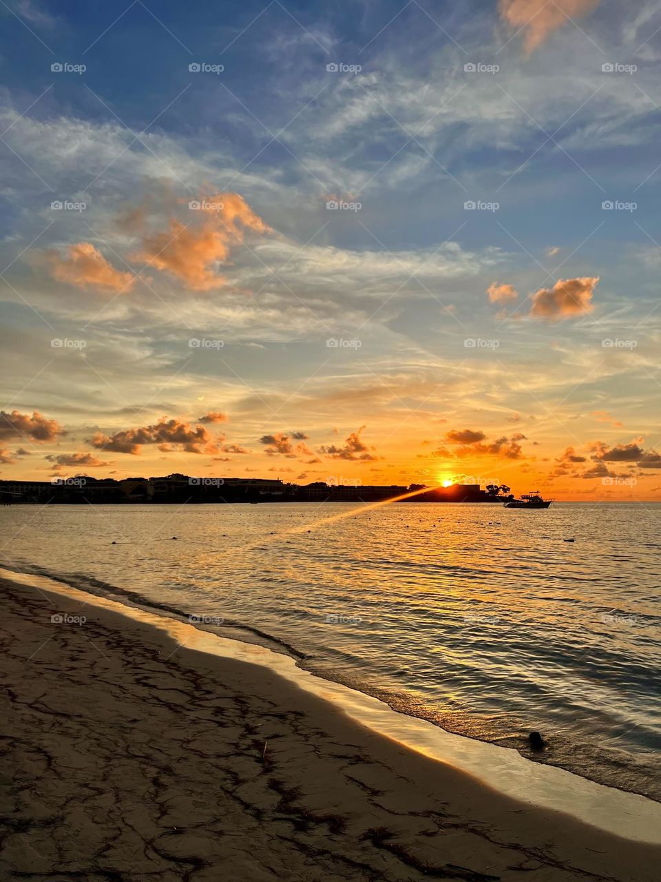 The surreal sunset on seven mile beach in Negril Jamaica, cascading hues of colors dazzle in the sky over the tranquil clear waters of the Caribbean 