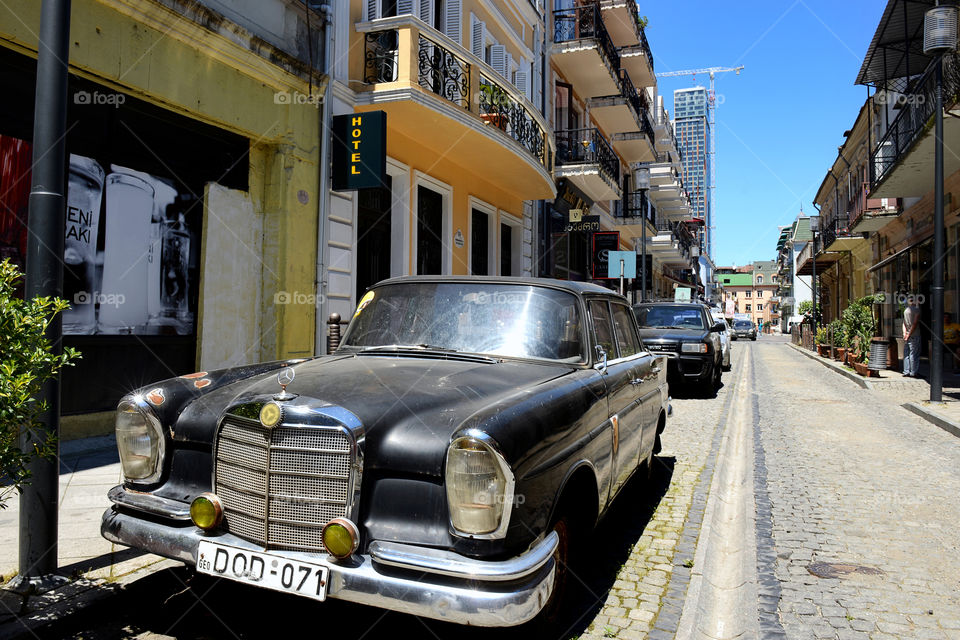 an old black Mercedes in a street background