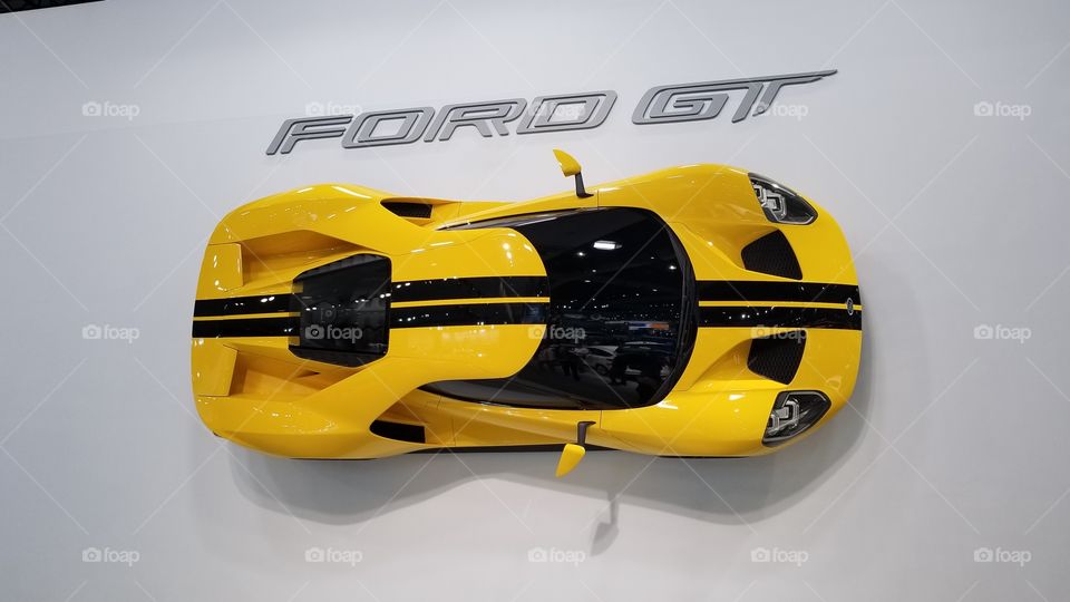 Yellow 2018 Ford GT mounted on the wall at a car show.