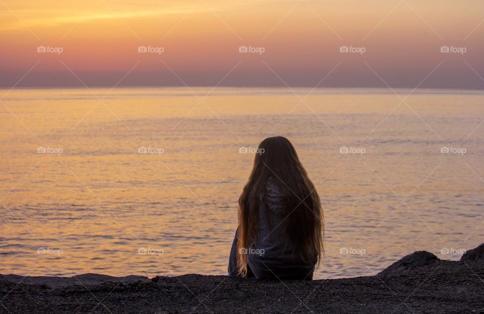 Woman looking at the sunrise over the sea