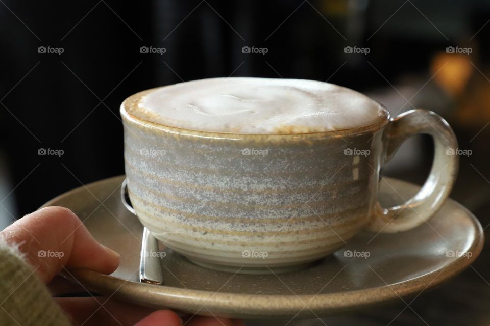 Hand holding a cup of cappuccino 