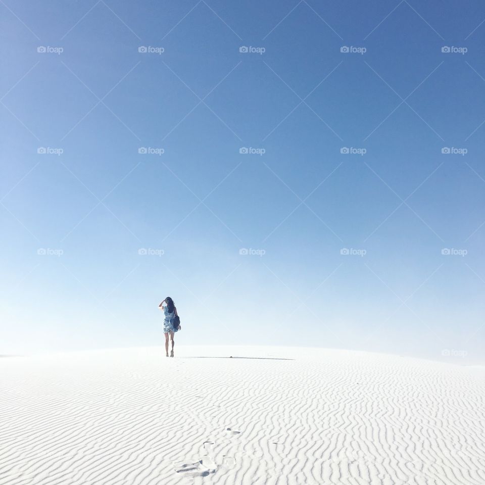 Rear view of a woman standing on sand dunes