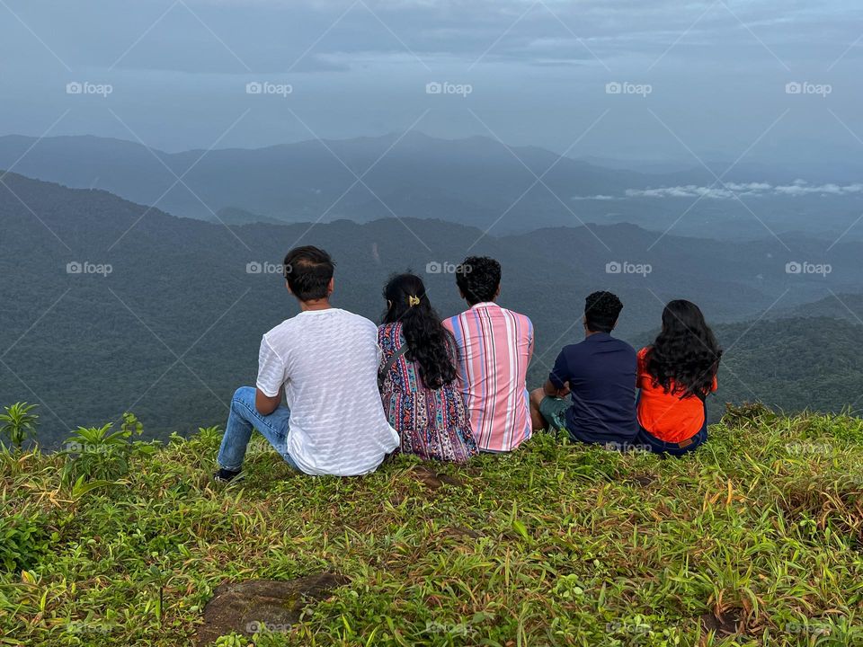 Group of friends sitting and enjoying on top of mountain 