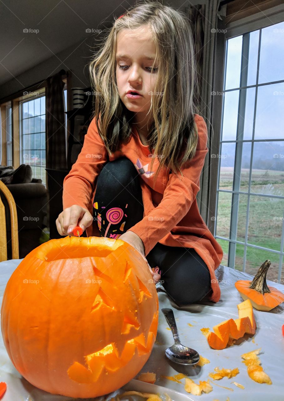 child carving a pumpkin